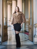 Woman in a fur coat and black skirt standing in an elegant interior setting