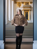 Woman wearing a fur coat and black knee-high boots in an elegant interior setting.