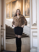 Woman wearing a fur coat and black knee-high boots in an elegant interior setting.