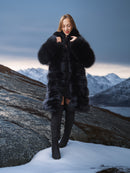 Woman in a black fur coat standing on a snowy mountain landscape