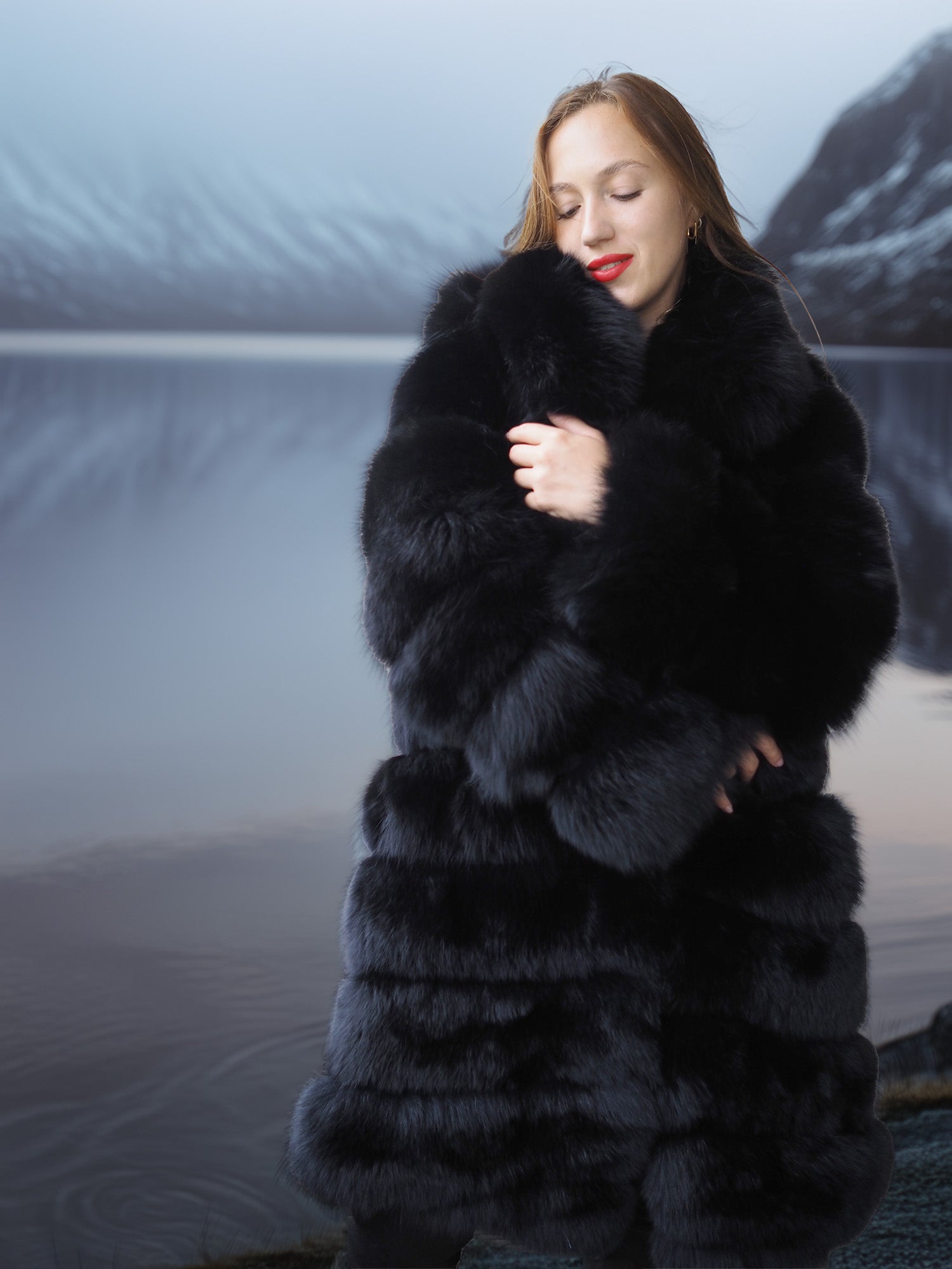 Woman wearing a long black fur coat with a mountainous background