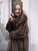 Close-up of woman smiling in luxurious dark brown mink fur coat, showcasing soft texture and elegant collar detail.