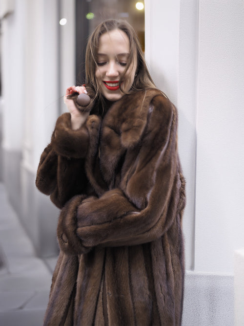 Close-up of woman smiling in luxurious dark brown mink fur coat, showcasing soft texture and elegant collar detail.