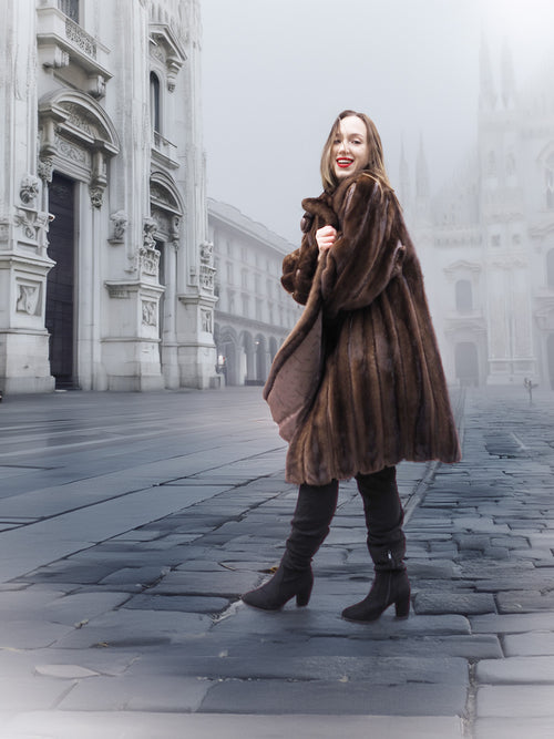 Model posing in vintage mink fur coat in a foggy cityscape, highlighting the coat's rich color and classic design.