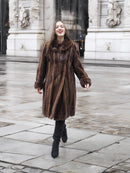 Dark mahogany brown mink fur coat worn in a city setting, highlighting its luxurious texture and timeless appeal.