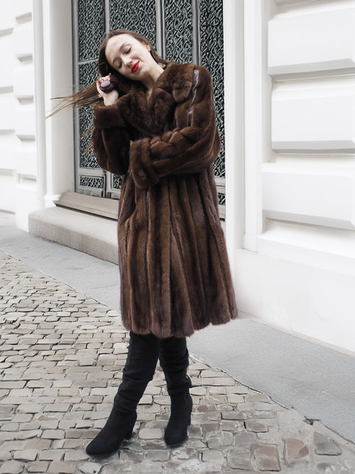 Woman leaning against a wall in a dark mahogany mink fur coat, perfect for medium sizes in luxury vintage outerwear.
