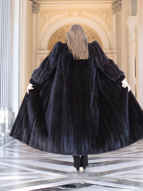 Back view of black mink fur coat flared out in motion, emphasizing its full volume and luxury. Premium winter outerwear, size M.