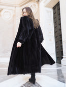 Back view of black mink fur coat in motion, highlighting its rich texture and volume. Elegant full-length outerwear, size M.