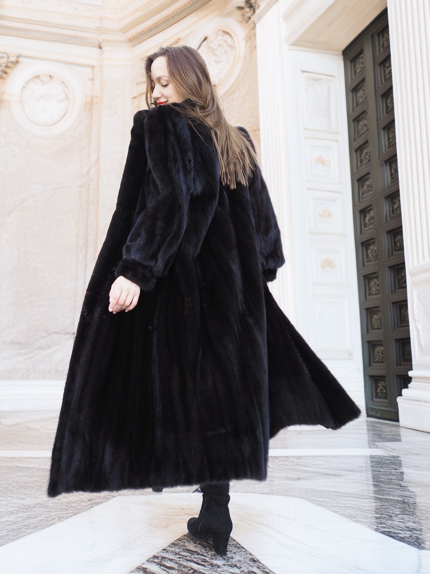 Back view of black mink fur coat in motion, highlighting its rich texture and volume. Elegant full-length outerwear, size M.