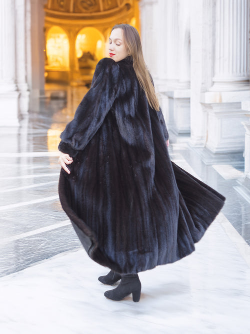 Luxury black mink fur coat with voluminous drape and soft sheen, twirling motion showcases full-length design. Premium winter outerwear, size M.