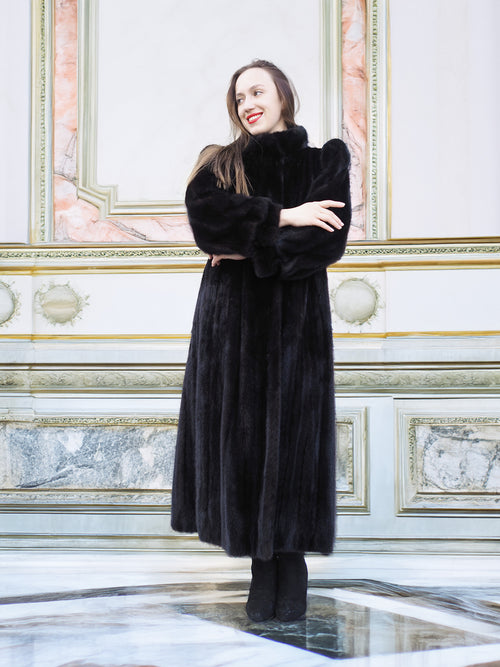 Full-length black mink fur coat with structured shoulders and plush texture, styled in a classic interior. Elegant cold-weather fashion, size M.