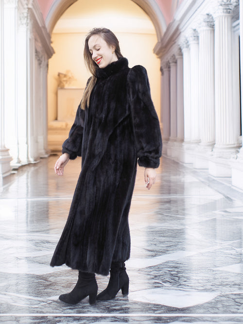 Model smiling in black mink fur coat with voluminous sleeves and soft texture. Elegant full-length winter coat, size M.