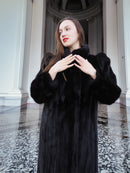 Model in black mink fur coat with hands raised, showcasing plush sleeves and elegant cut. Full-length winter coat, size M.