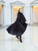 Flowing black mink fur coat in motion, highlighting its regal volume and luxurious sheen. Full-length fur fashion for winter, size M.