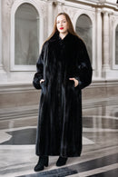 Woman wearing a long black fur coat in an elegant interior setting