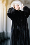 Woman wearing a black fur coat in an indoor setting