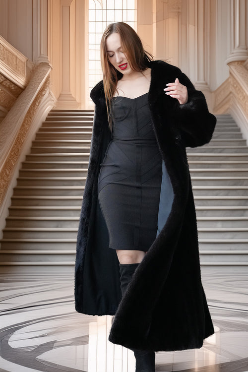 Woman in a black dress and coat standing on a staircase