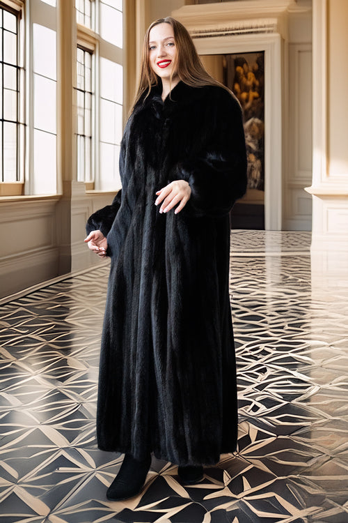Woman wearing a long black coat in an elegant interior setting