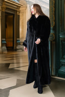 Woman wearing a long black coat in an elegant interior setting