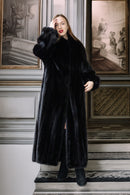 Woman wearing a black fur coat standing on a staircase with classical wall decorations.