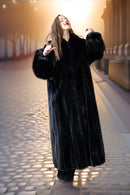 Woman wearing a black fur coat standing on a stone pavement.