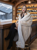 Woman in a fur coat sitting at a bar with a mountain view