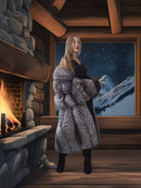 Woman in a fur coat standing in a cabin with a fireplace and mountain view.