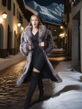 Woman in a fur coat standing on a snowy street with mountains in the background