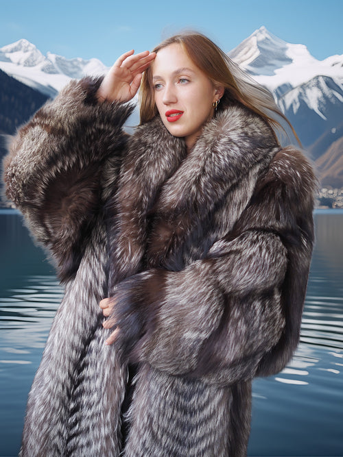 Woman in a fur coat standing in front of a mountainous landscape with a lake.