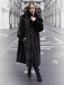 Model poses in a black mink fur coat with hands in pockets, showcasing the coat's rich texture and timeless elegance.