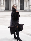 Black mink fur coat with a flowing silhouette, styled with boots for a fashionable and cozy winter outerwear look.