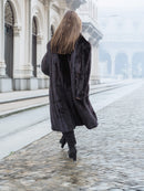 Back view of a black mink fur coat in motion, revealing its voluminous and luxurious design for winter fashion.