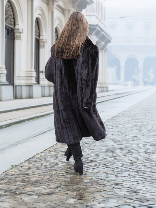 Back view of a black mink fur coat in motion, revealing its voluminous and luxurious design for winter fashion.