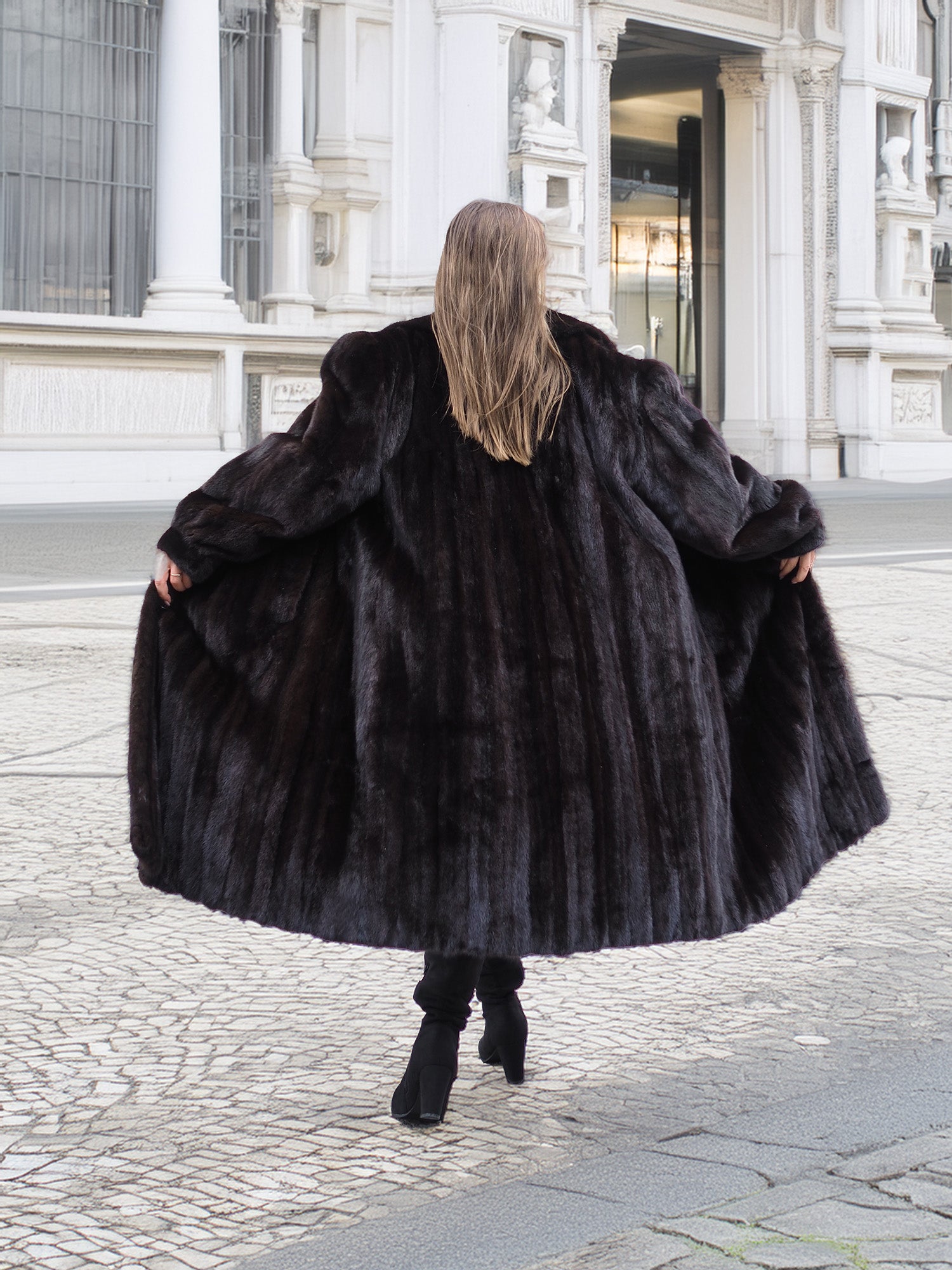 Back view of a flowing black mink fur coat, emphasizing its rich texture and dramatic luxury outerwear style.