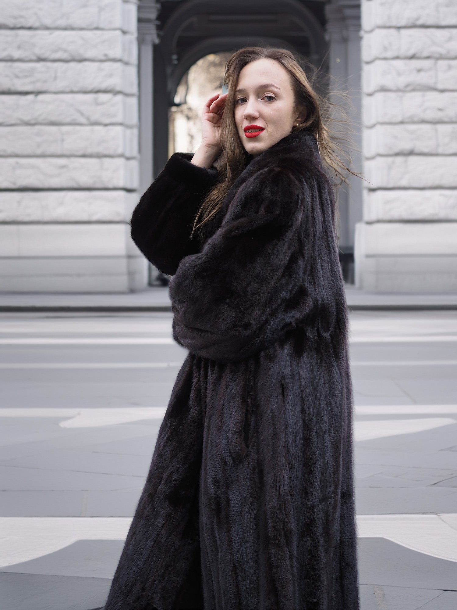 Side profile of a model in a black mink fur coat, showcasing the coat’s soft finish and elegant winter fashion appeal.