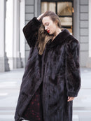 Model in a black mink fur coat with hand in hair, highlighting the coat’s plush texture and stylish collar design.