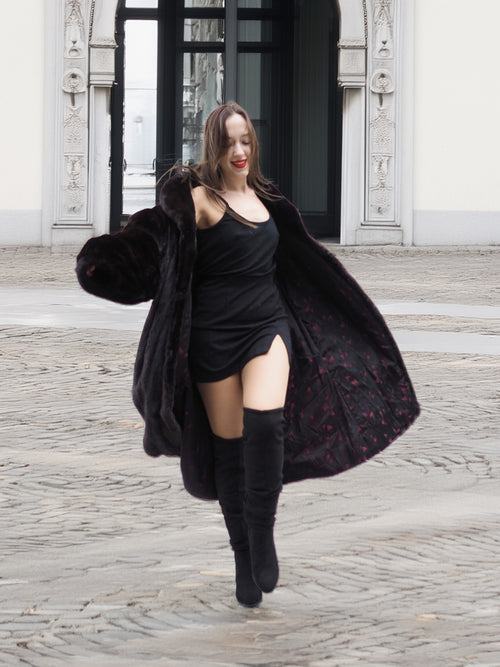 Model twirling in a black mink fur coat, revealing the patterned inner lining and luxurious movement of the coat.