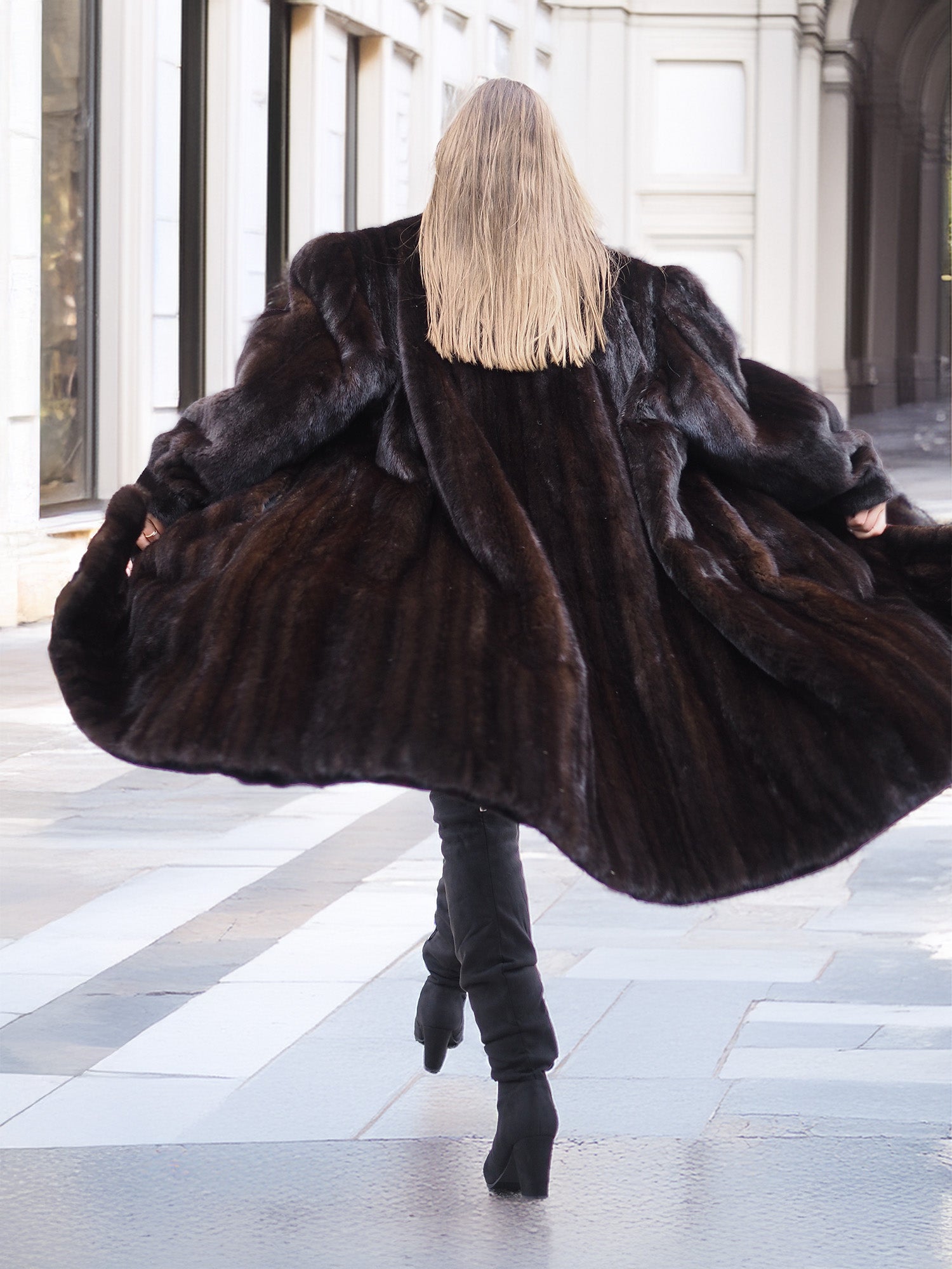 Dark ranch black mink fur coat shown from the back, flared open to reveal its voluminous and plush design, ideal for luxury winter wear.