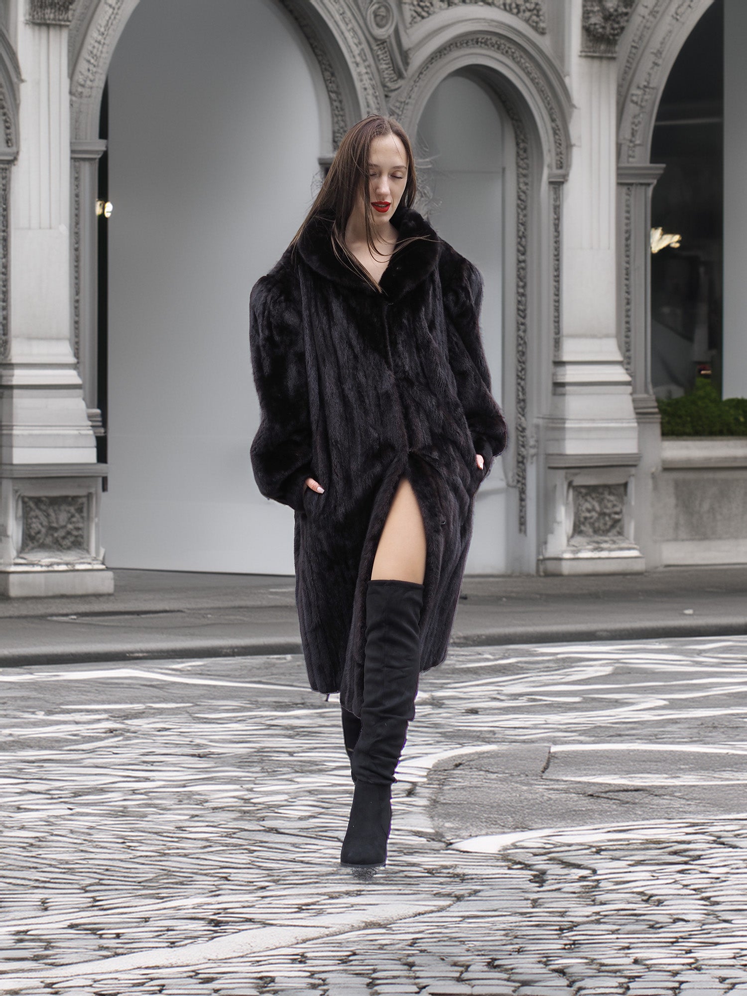 Full-length black mink fur coat styled with thigh-high boots, perfect for elegant winter fashion in urban settings.