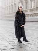 Model in a black mink fur coat walking on a foggy street, highlighting the coat’s warmth and luxurious appeal.