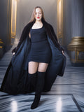 Woman in a black outfit with a long coat in an elegant interior setting