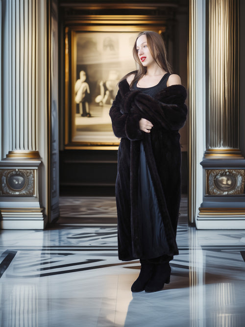 Woman in a black coat standing in an elegant interior setting with classical architecture.