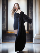 Woman holding a black coat in an elegant interior setting