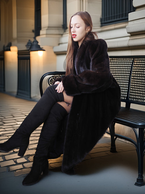 Woman in a dark coat sitting on a bench in an urban setting