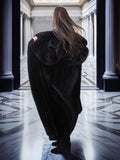 Person wearing a dark coat in a grand hallway with columns