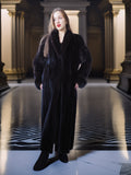 Woman wearing a long black coat in an elegant interior setting