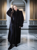 Woman wearing a long black coat in an elegant interior setting