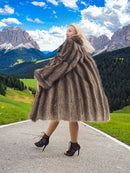 a woman in a fur coat walking down a road