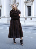 Woman in full-length mink fur coat, city backdrop