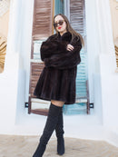 Riviera Noir Black Mink Swing Coat in motion on a wooden deck by the sea. Luxurious mink coat for stylish cold-weather outfits.